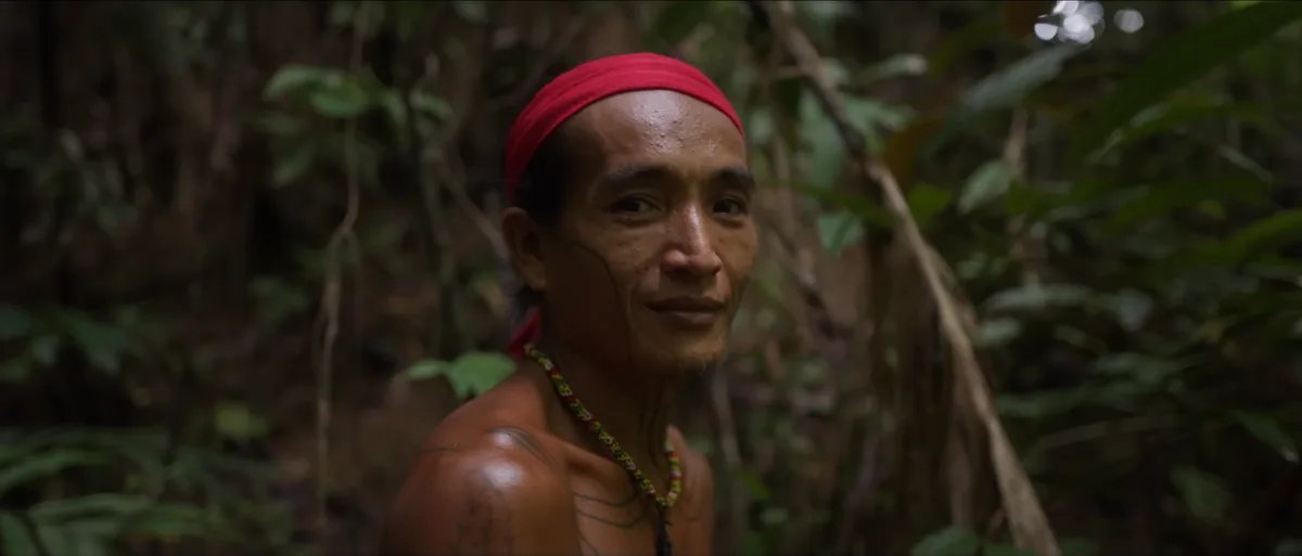 Femme mentawai tatouée souriant au bord d'une rivière dans la jungle de l'île de Siberut dents limées tradition