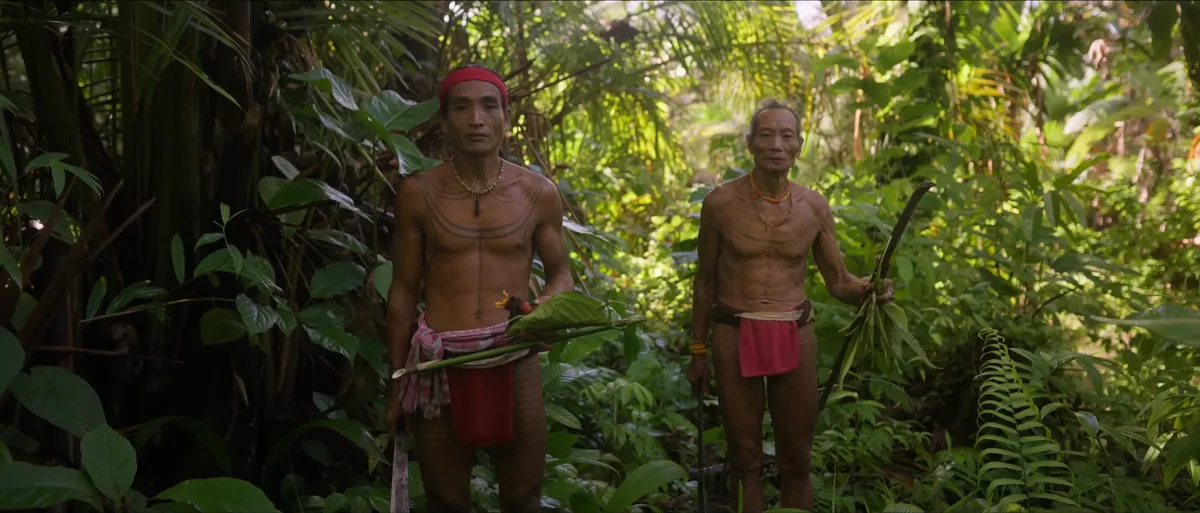 Deux hommes mentawai tatoués debout dans la jungle dense de Siberut pagnes traditionnels chasseurs île Mentawai