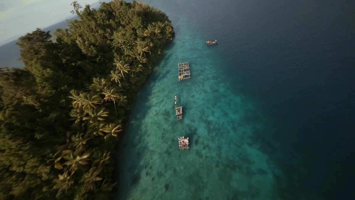 Vue aérienne d'une côte tropicale avec des structures de pêche bajau flottant sur une eau cristalline en Indonésie