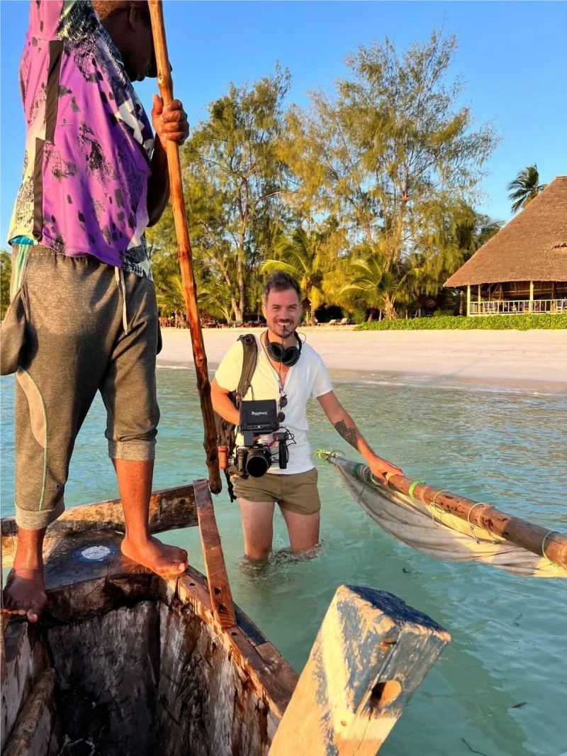 Vidéaste solo filmant un documentaire en Tanzanie caméra à la main dans l'eau avec un pêcheur local