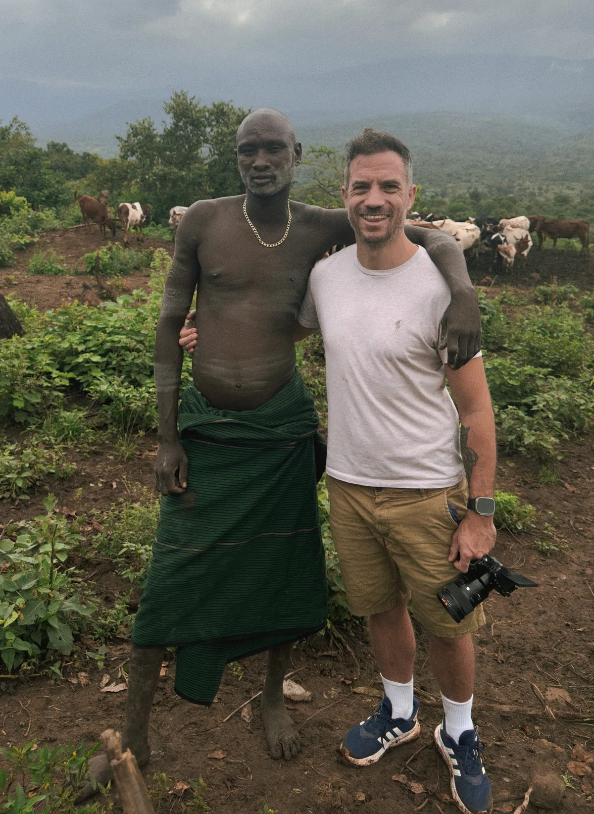 Vidéaste documentaire posant avec un membre d'une tribu locale en Éthiopie caméra à la main tournage solo terrain